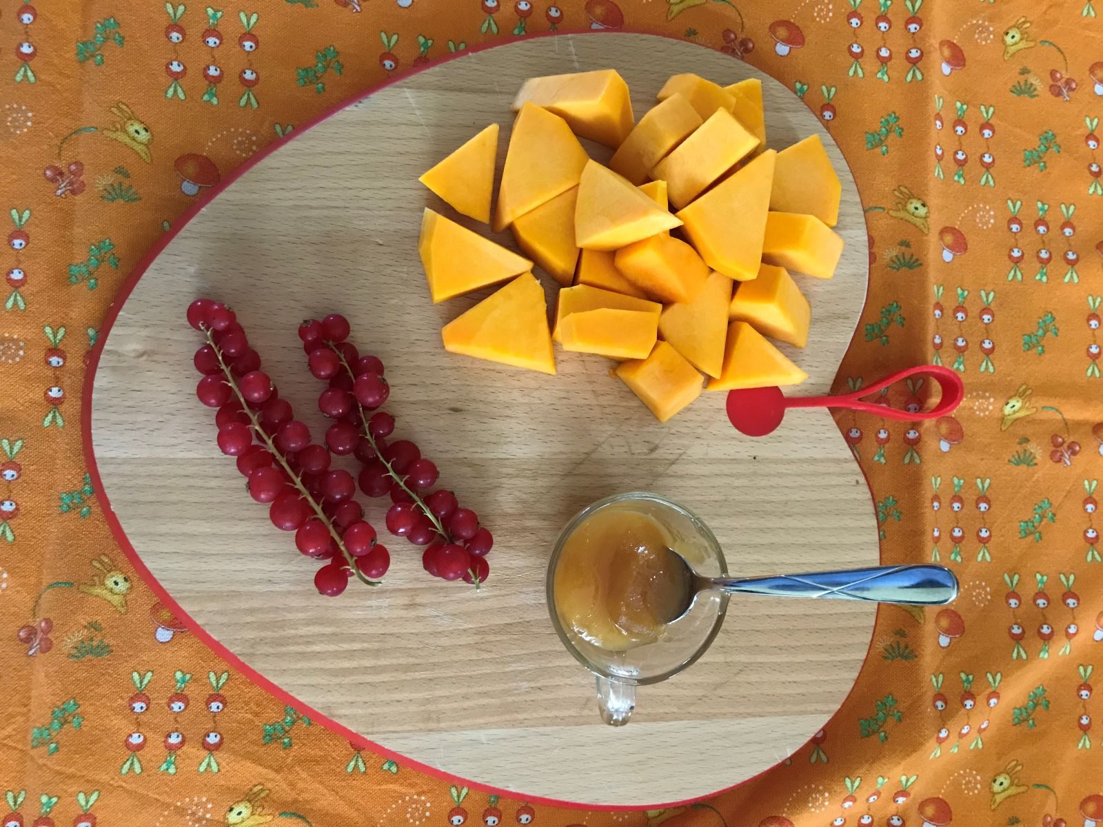 un tagliere a forma di cuore ospita della zucca arancione a dadini, due rametti di riber e una tazzina con del miele. Il tagliere poggia su una tovaglia arancione