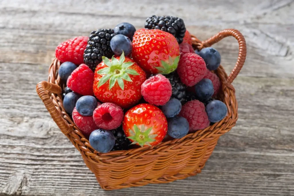 cestino di vimini ricolmo di fragole, mirtilli, lamponi e altri frutti di bosco