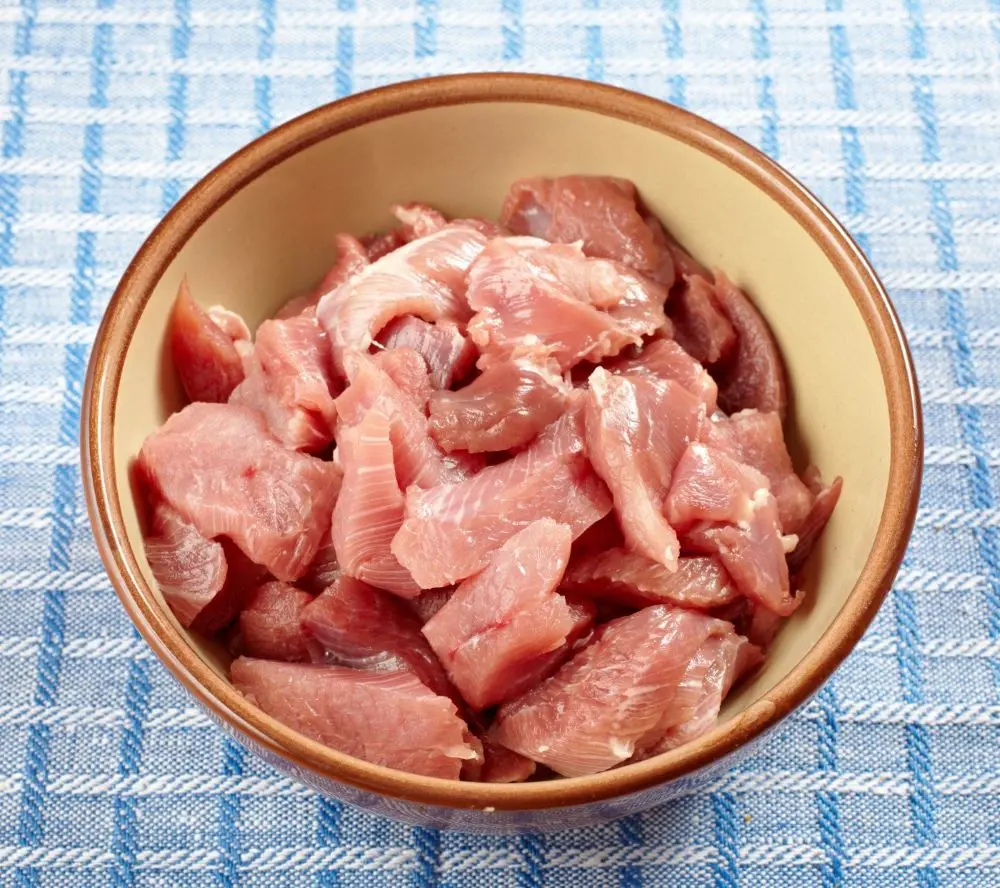 piatto fondo in coccio con pezzi di carne di tacchino su tovagli ascacchi azzurri