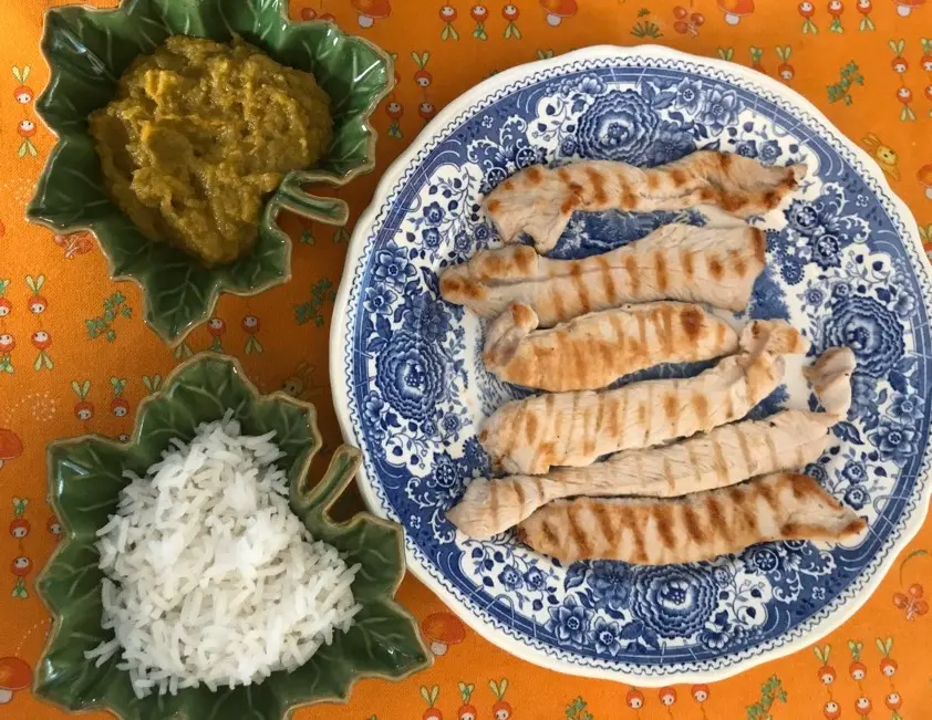 Piatto con tacchino grigliato e due ciotole a forma di foglia con riso e zucca