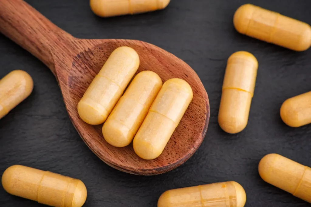 cucchiaio di legno con capsule di Boswellia serrata su sfondo nero