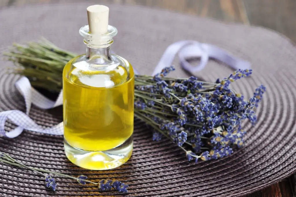 Boccetto di olio essenziale di lavanda, accanto un mazzo di landa essiccata su stuoia del colore dei fiori di lavanda