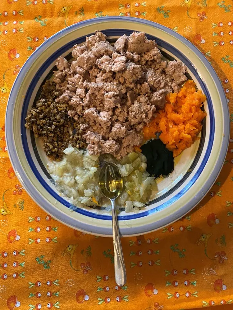 piatto in ceramica a righe blu, su tovaglia arancio, con tutti gli ingredienti della ricetta