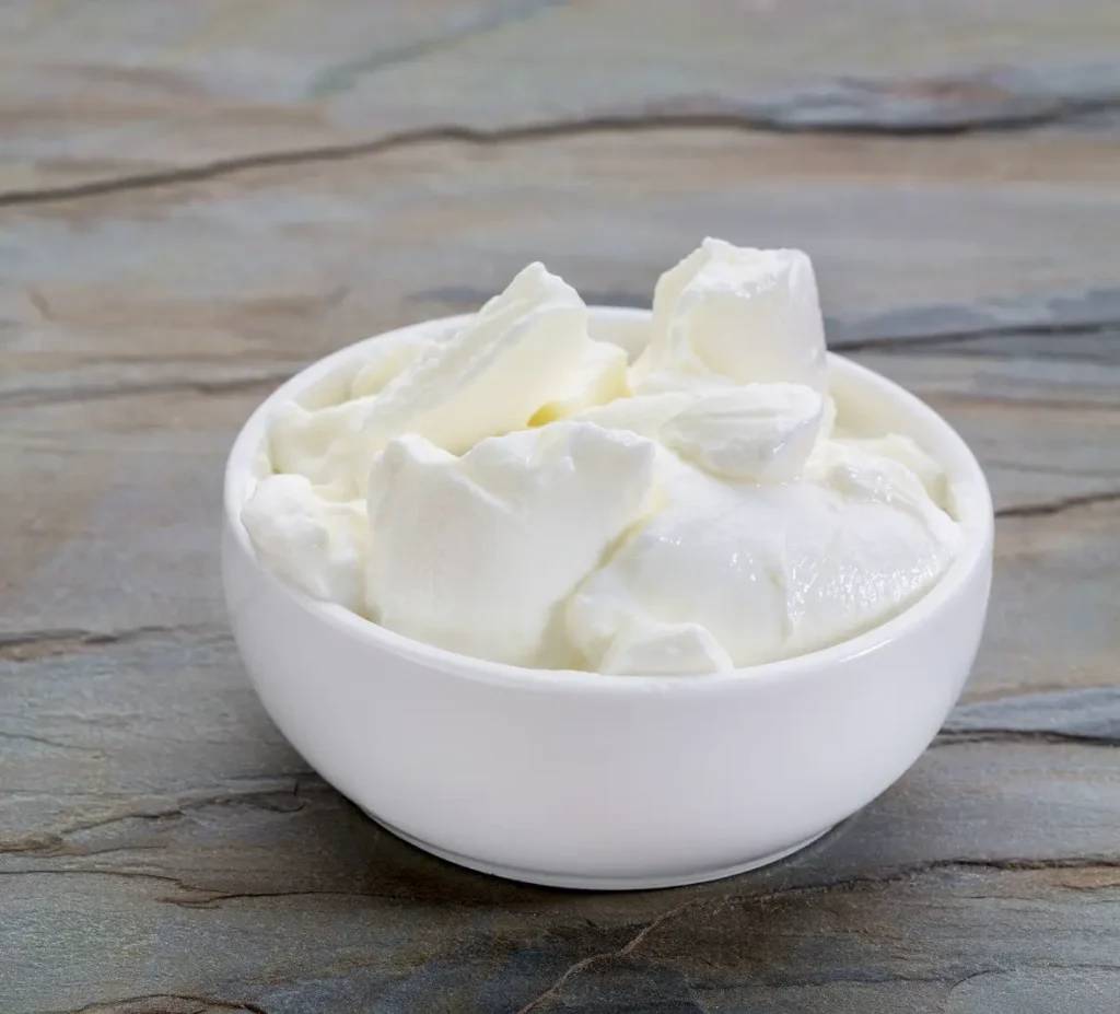 ciotola in ceramica bianca con yogurt greco, su tavolo grigio
